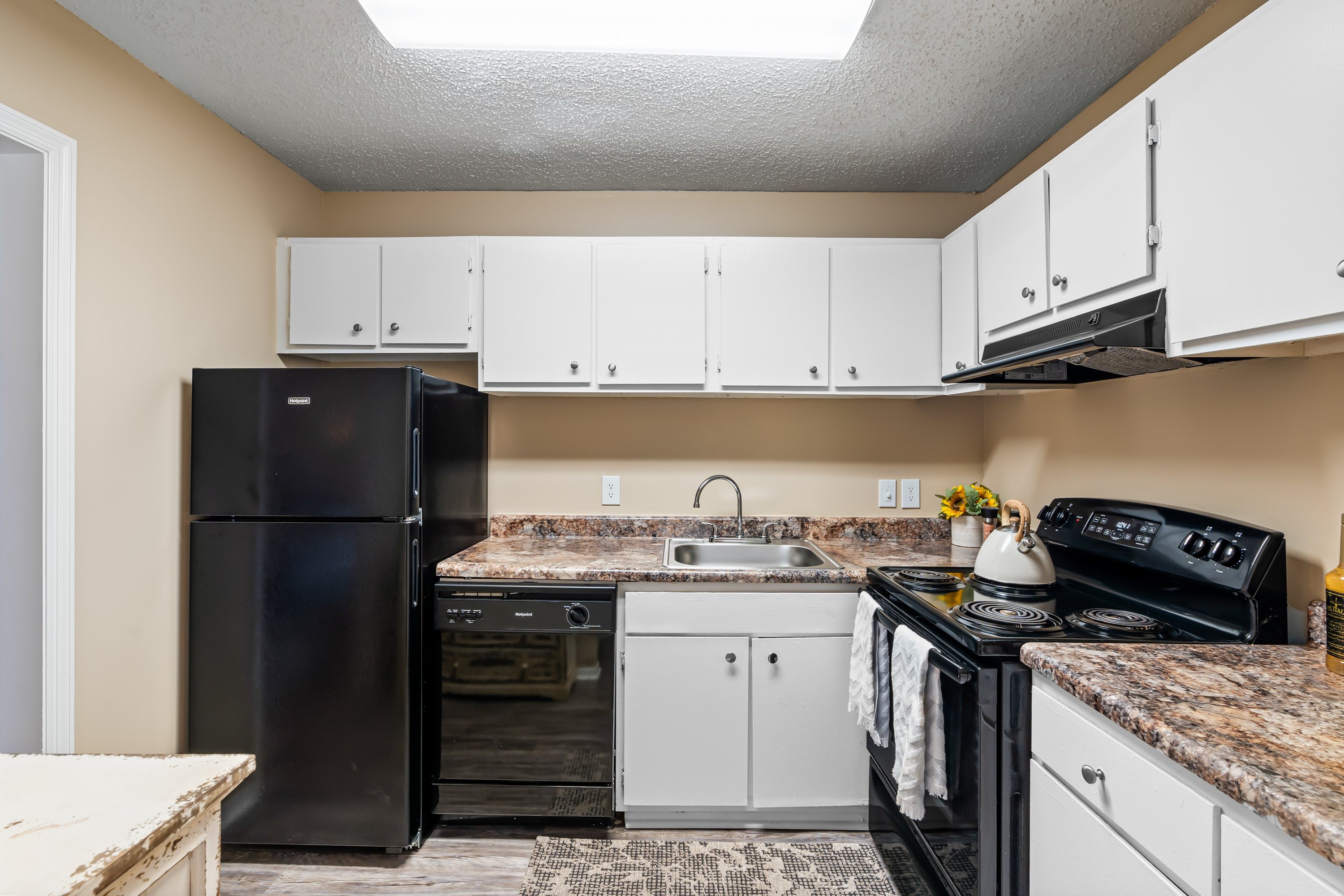A kitchen with black appliances and white cabinets.